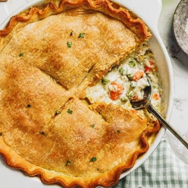 Square overhead shot of a serving spoon in a chicken pot pie with pie crust.