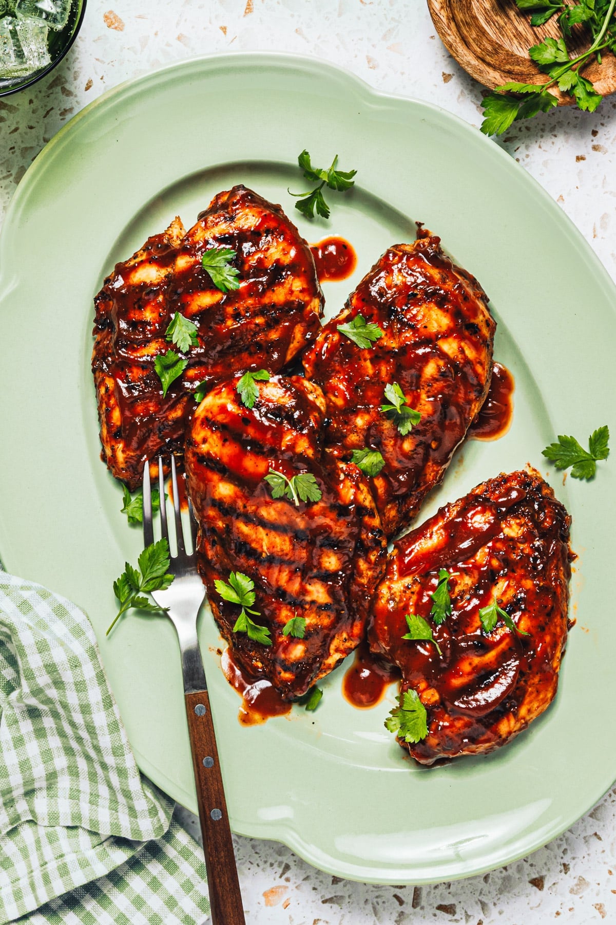 Overhead shot of grilled bbq chicken breast on a green serving tray.