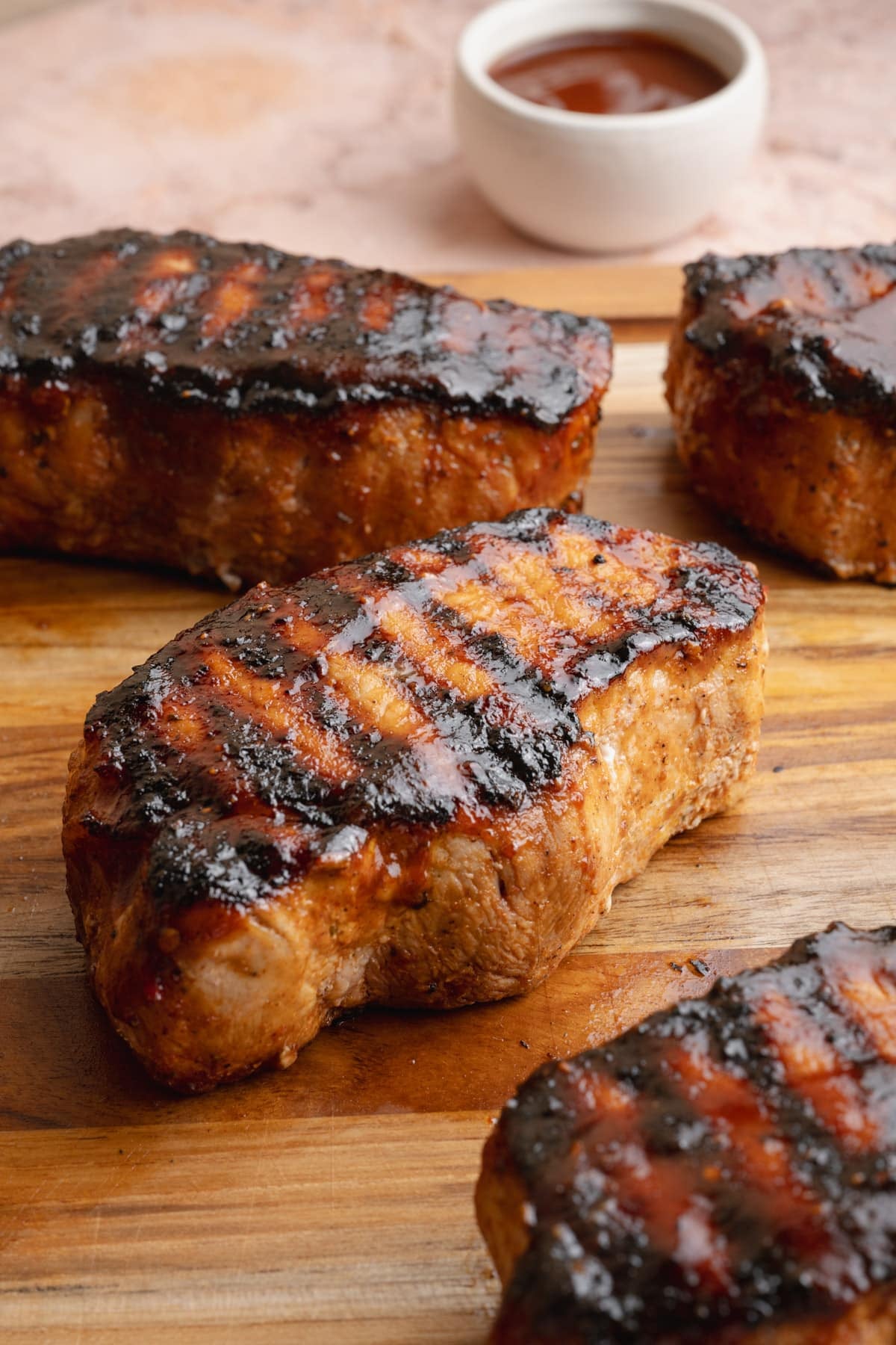 Side shot of grilled bbq pork chops on a cutting board.