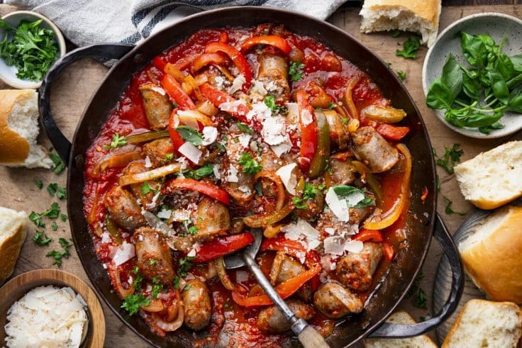 Horizontal overhead image of a round cast iron skillet full of old fashioned Italian sausage and peppers.