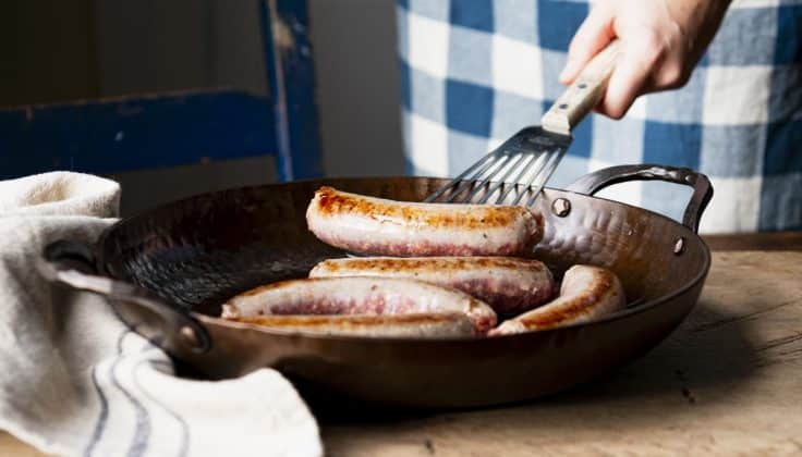 Browning Italian sausage links in a skillet.