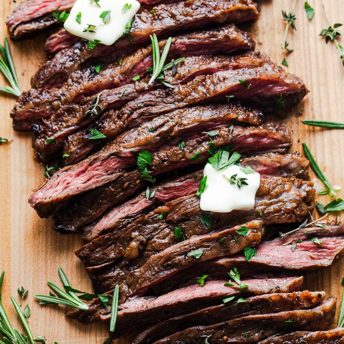 Sliced marinated London broil on a wooden cutting board.