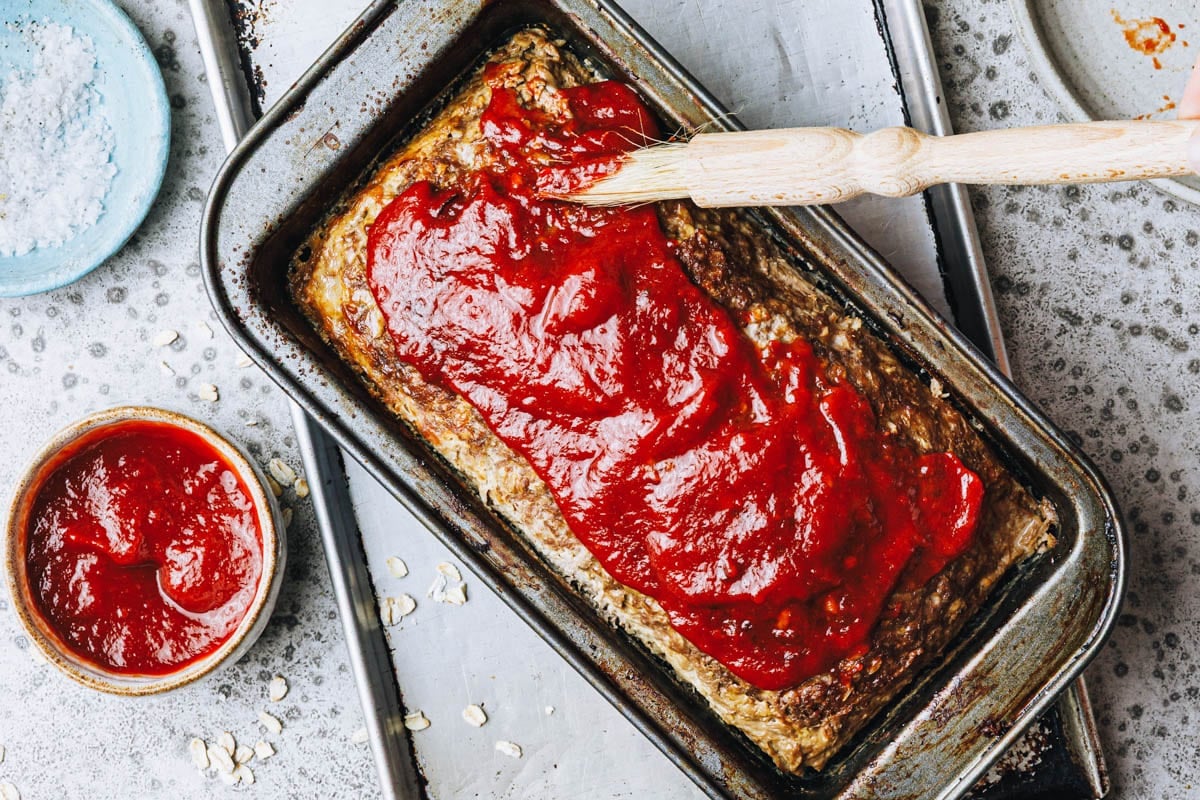 Spreading ketchup on top of meatloaf.