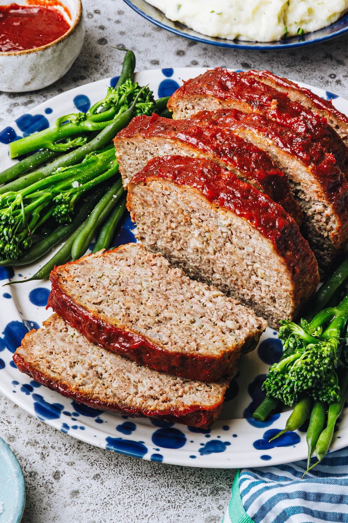 Side shot of a sliced meatloaf recipe with oatmeal on a blue and white platter.
