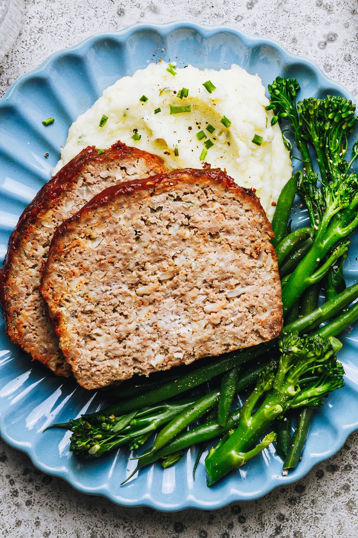 Overhead shot of a plate of meatloaf with mashed potatoes and broccoli.