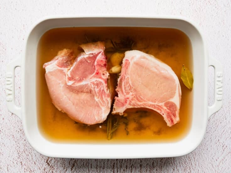 Bone-in pork chops in a garlic and rosemary pork chop brine.