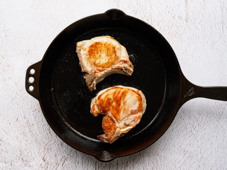Cooking brined pork chops in a cast iron skillet.