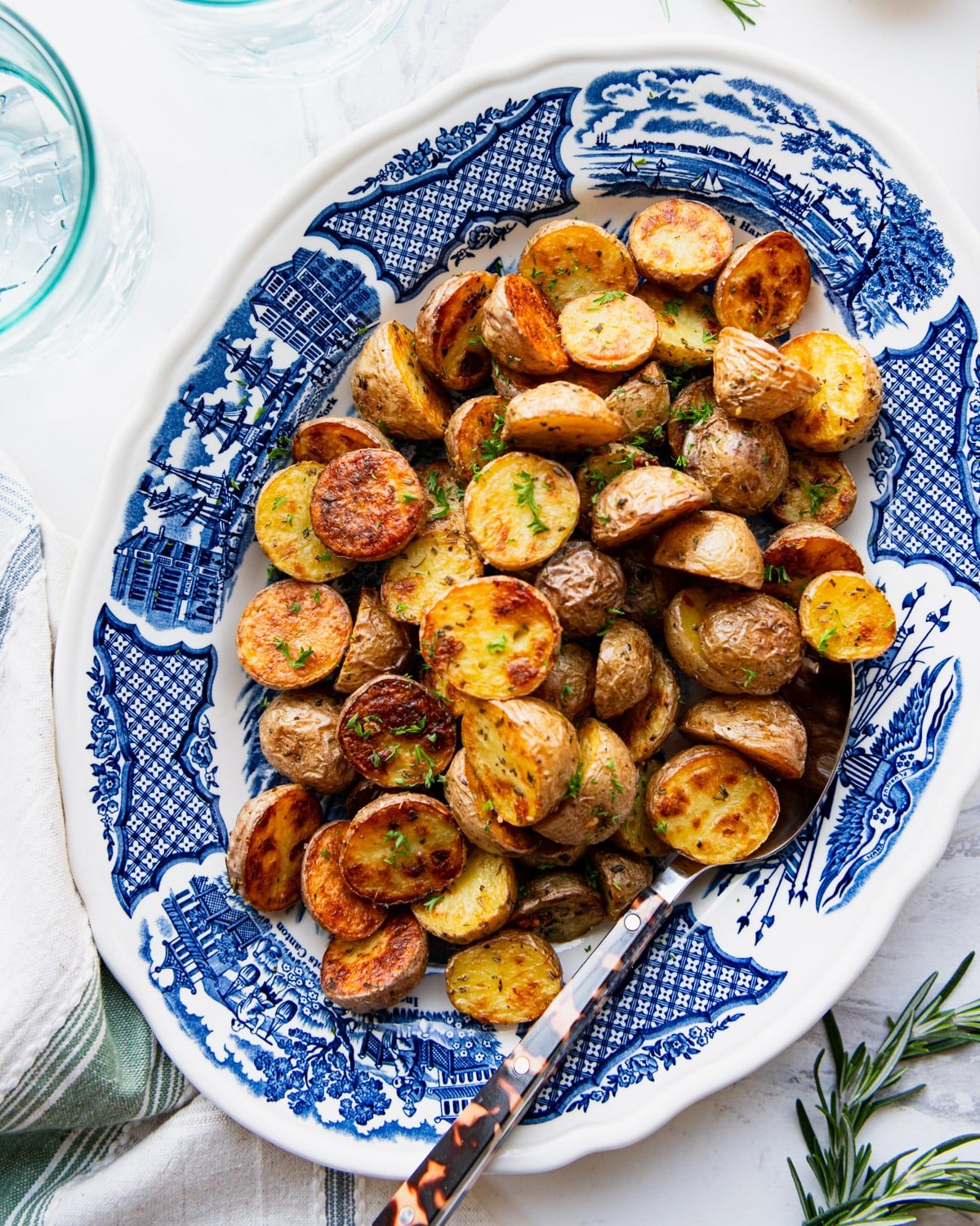Overhead shot of roasted golden potatoes on a blue and white serving platter.