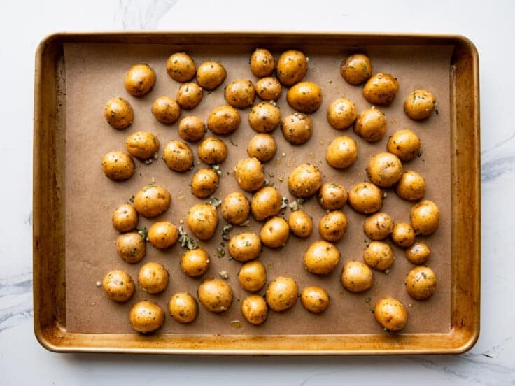 Gold potatoes spread on a sheet pan.