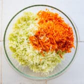Shredded cabbage and carrots in a large glass bowl.