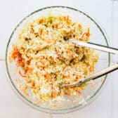 Tossing the vegetables with the coleslaw dressing.