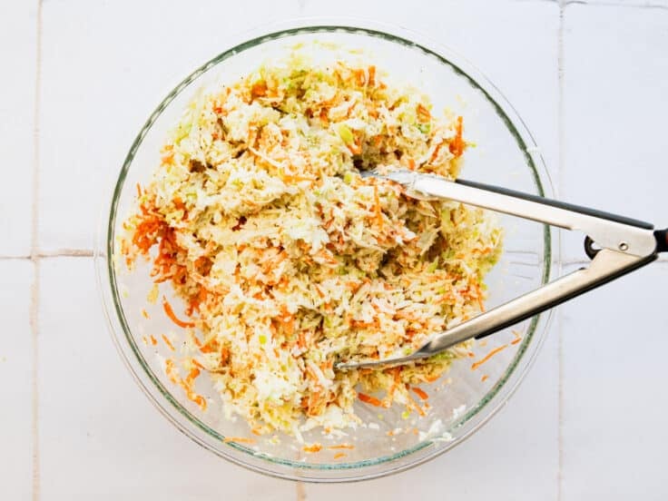 Tossing the vegetables with the coleslaw dressing.
