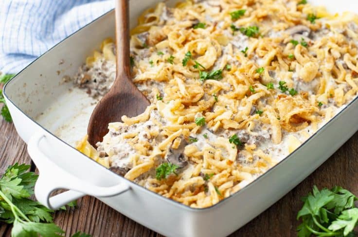 Horizontal shot of a spoon in a dish of hamburger stroganoff casserole with cream of mushroom soup.