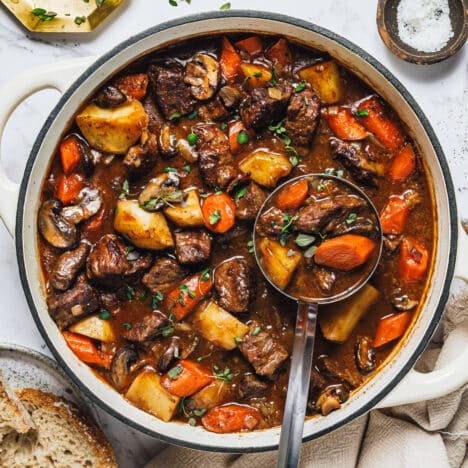 Square overhead image of a ladle in a pot of Dutch oven beef stew.