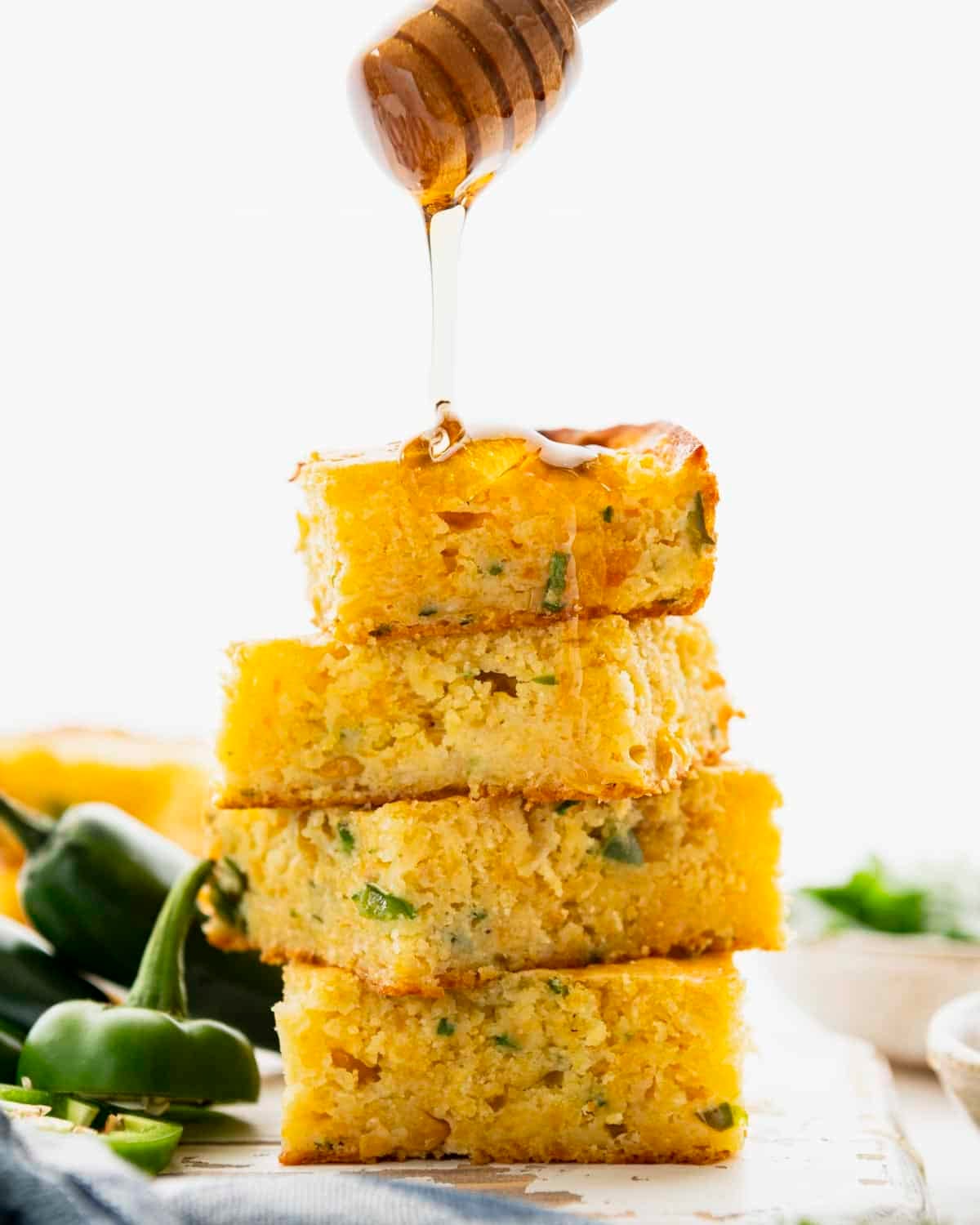 Drizzling honey on four squares of Jiffy Mexican cornbread.