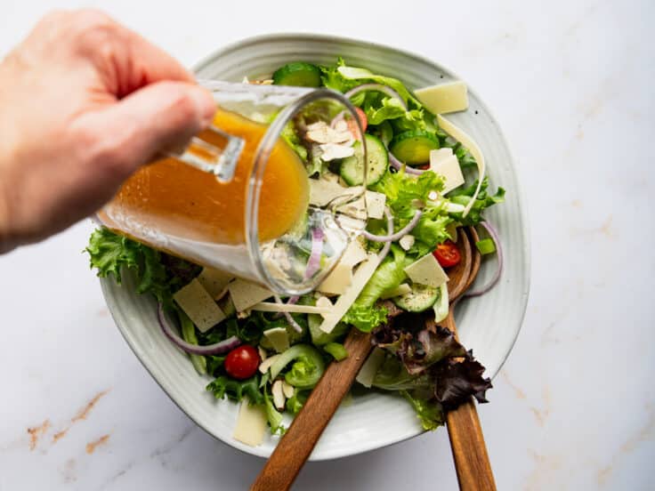 Drizzling red wine vinaigrette over a green salad.