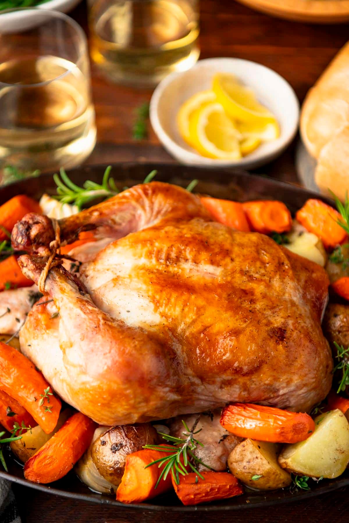 Side shot of a roast chicken and vegetables in a cast iron pan.