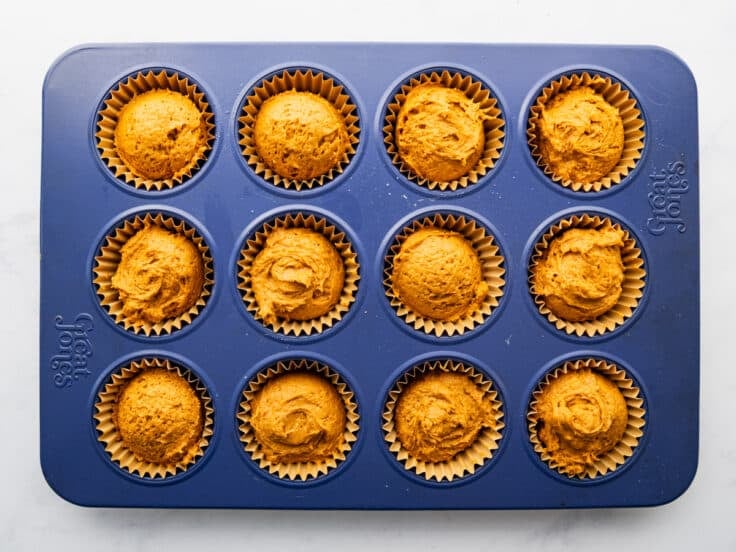 Two ingredient pumpkin muffin batter in a blue muffin tin.