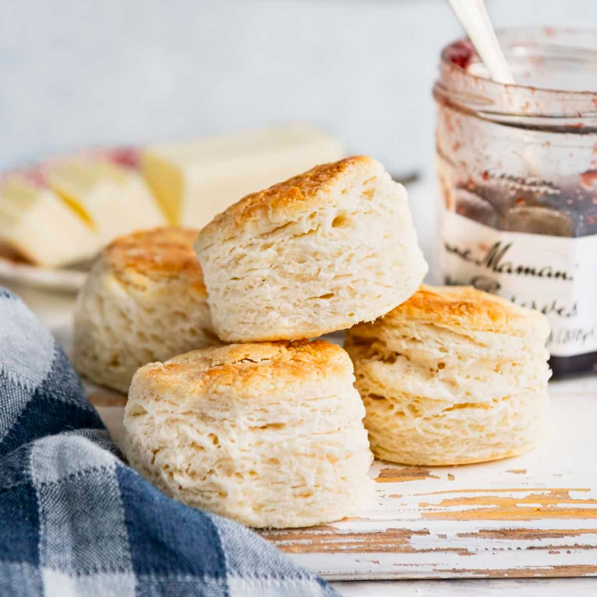 Square side shot of a pile of homemade biscuits on a white table.