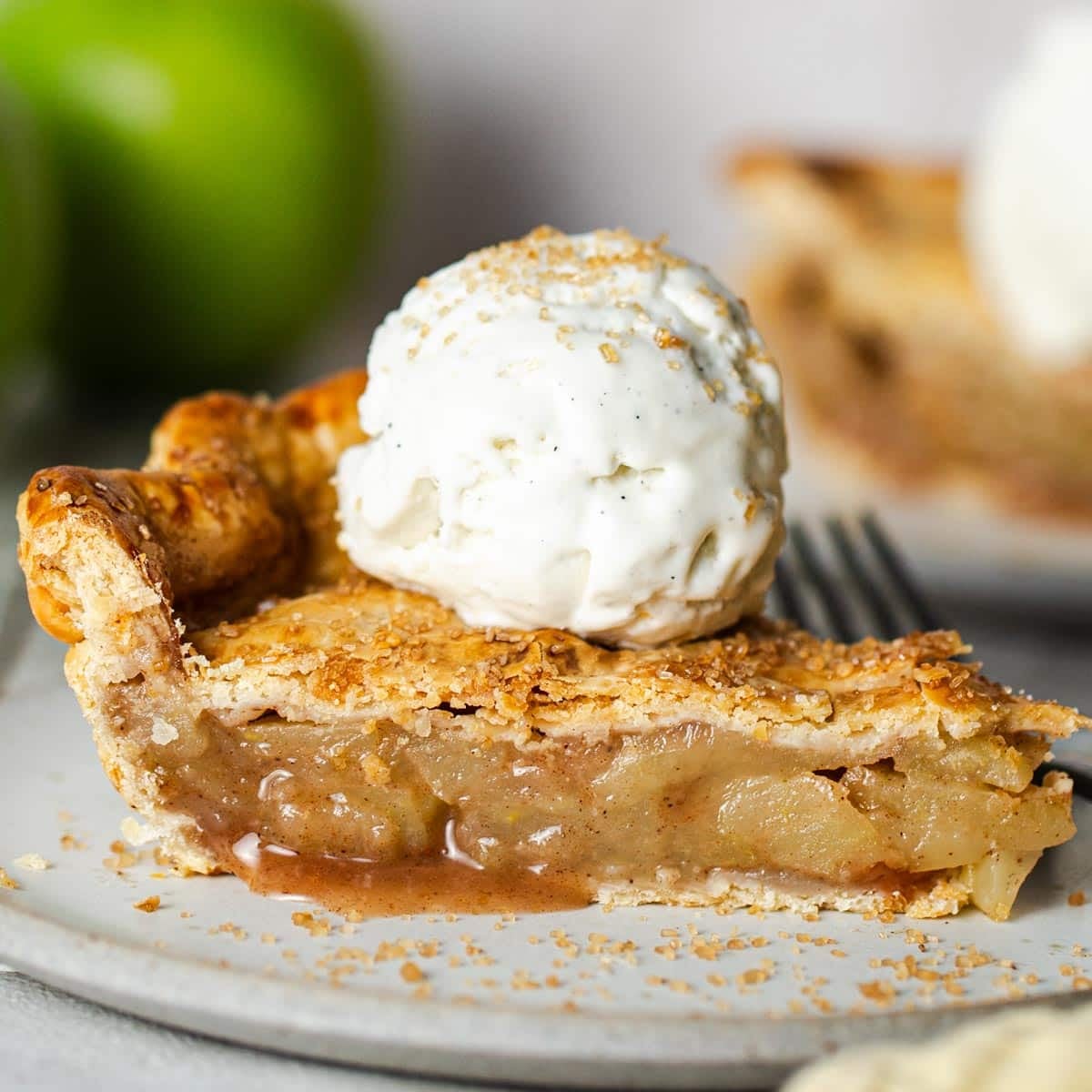 Square side shot of a slice of easy apple pie with ice cream on top.