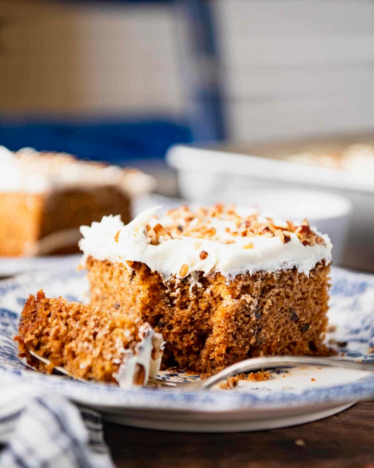Front shot of a bite of carrot cake on a fork on a plate.