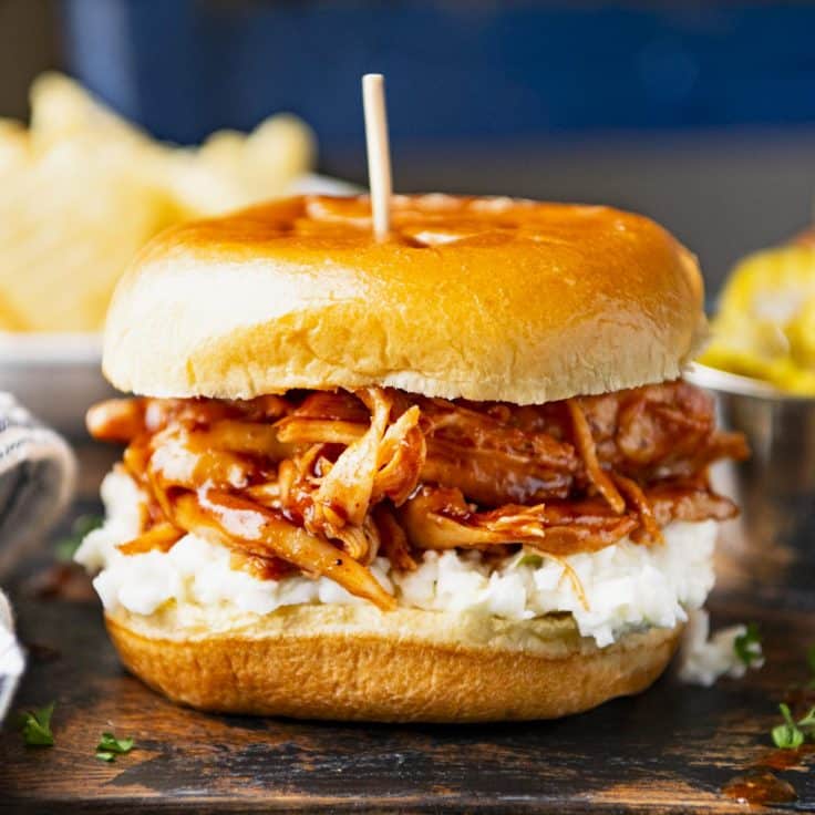 Square side shot of Crock Pot bbq pulled chicken on a sandwich with coleslaw.