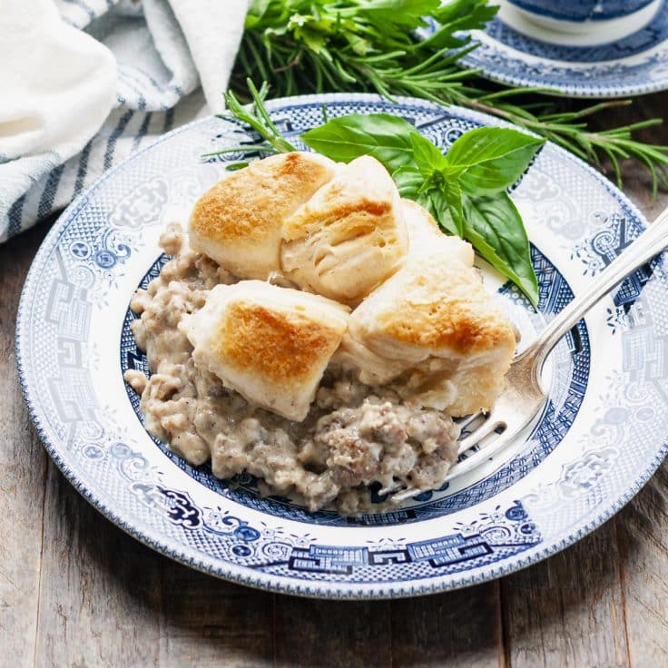 Square side shot of a plate of biscuits and gravy breakfast casserole.