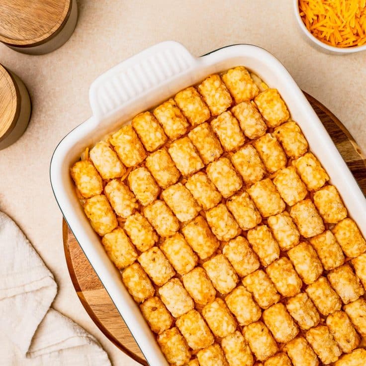 Arranging frozen tater tots on a chicken casserole.