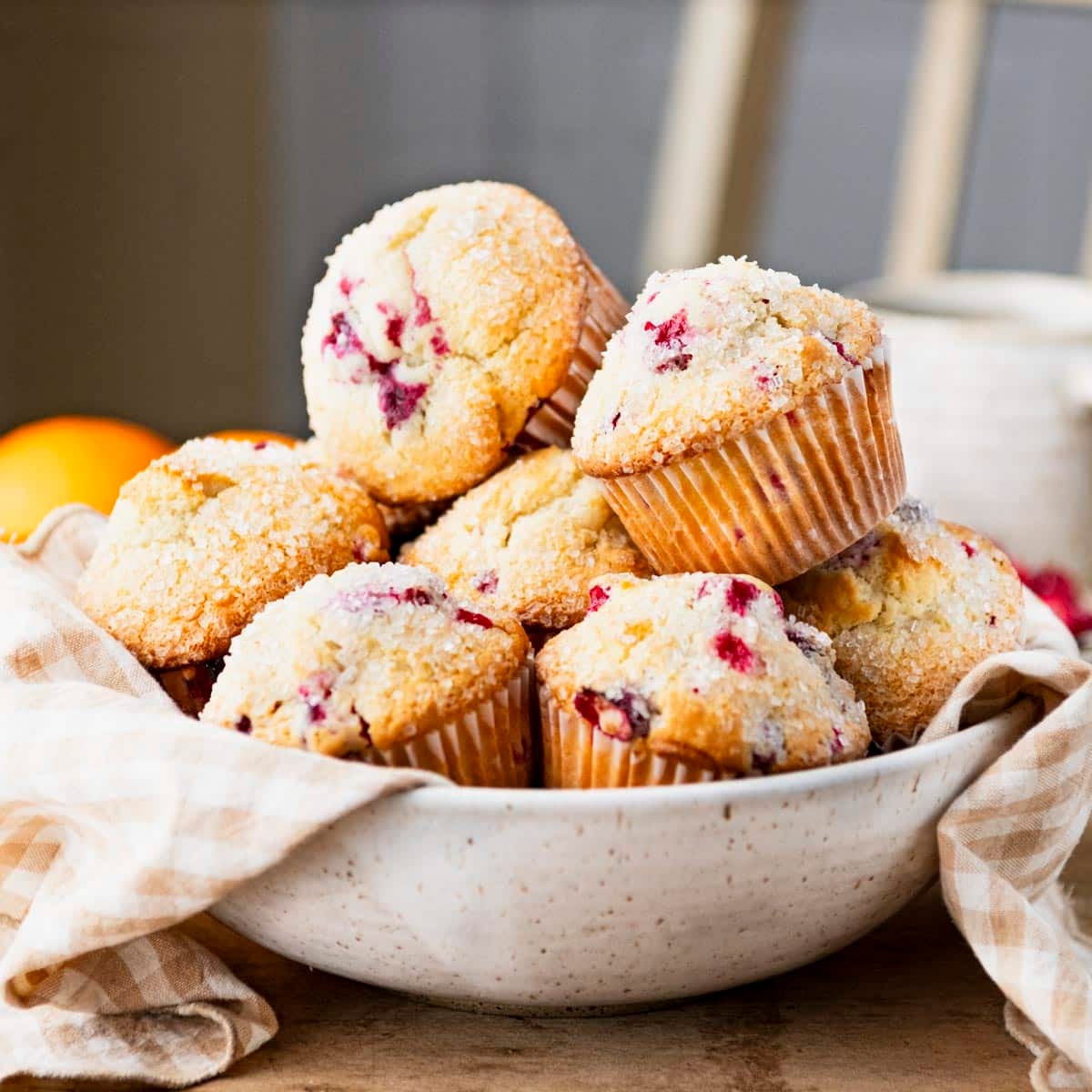Square side shot of a bowl of orange cranberry muffins.