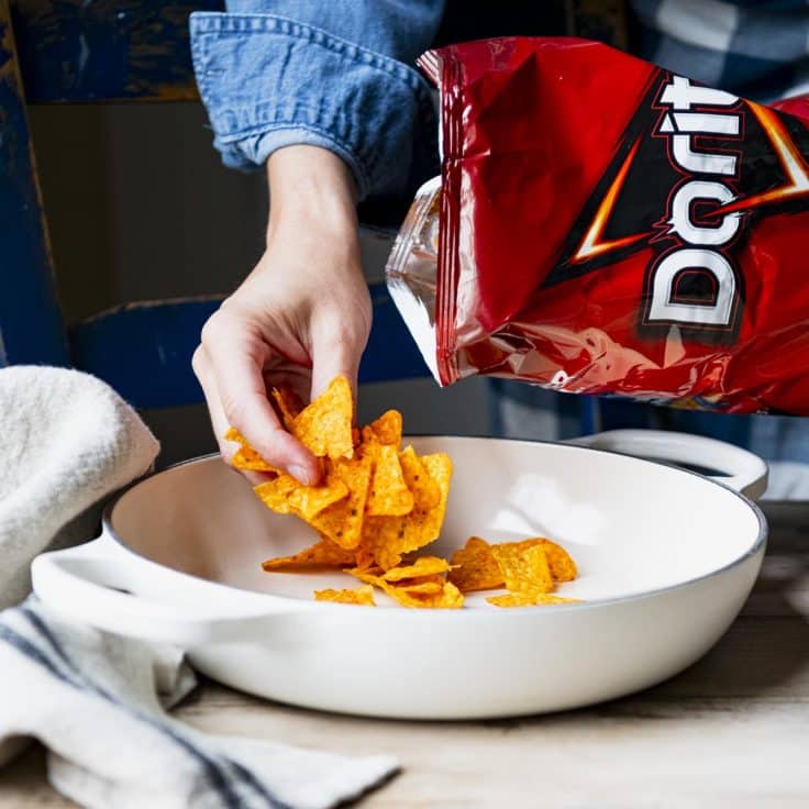 Placing Doritos in the bottom of a baking dish.