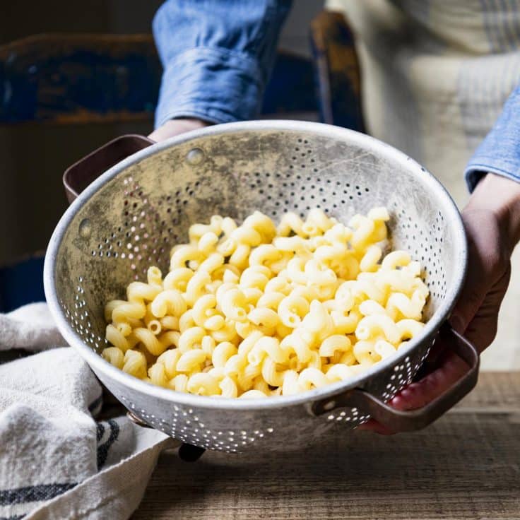 Boiled macaroni pasta draining in a colander.