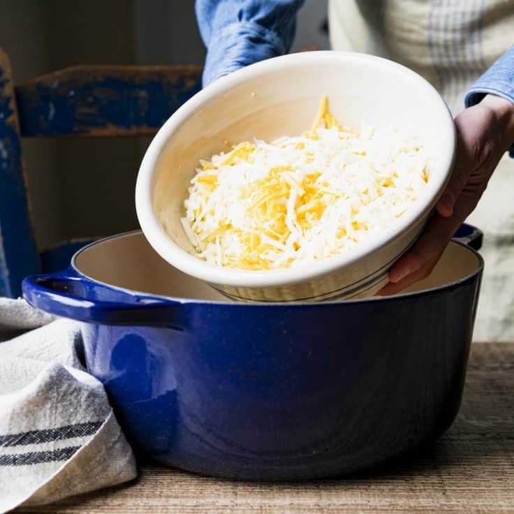 Adding cheese to a Dutch oven.