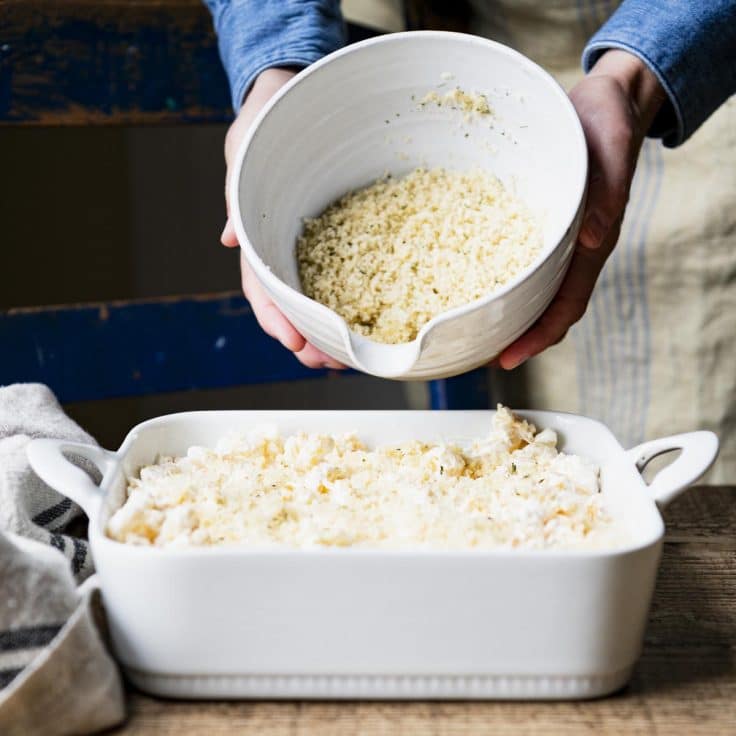 Adding breadcrumbs to the top of homemade mac and cheese before baking.