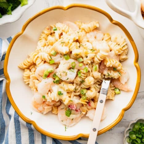 Square overhead shot of dump and bake shrimp Alfredo in a bowl on a white table.