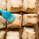 Brushing melted butter on the tops of the baked biscuits.