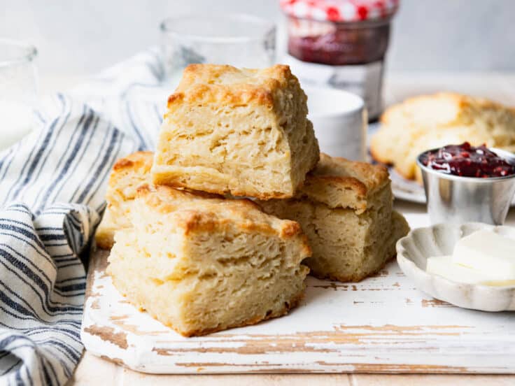 Horizontal side shot of flaky biscuits on a white wooden board.