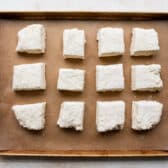 Square cut out biscuits on a baking sheet.