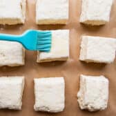 Brushing melted butter on biscuits before they go in the oven.
