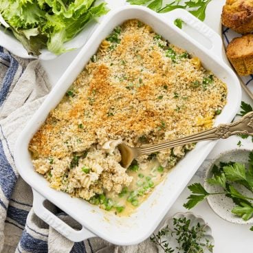 Square overhead shot of leftover turkey casserole in a white baking dish on a dinner table.