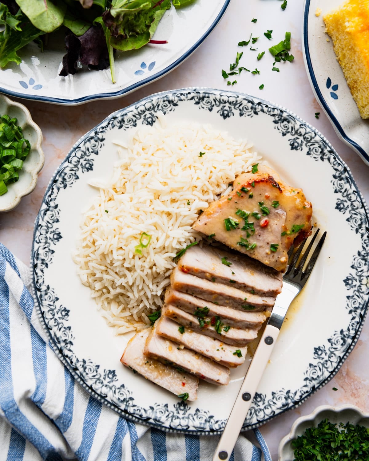 Overhead shot of a sliced oven baked pork chop on a dinner plate with a side of rice.