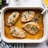 Horizontal overhead shot of baked pork chops in a white dish.