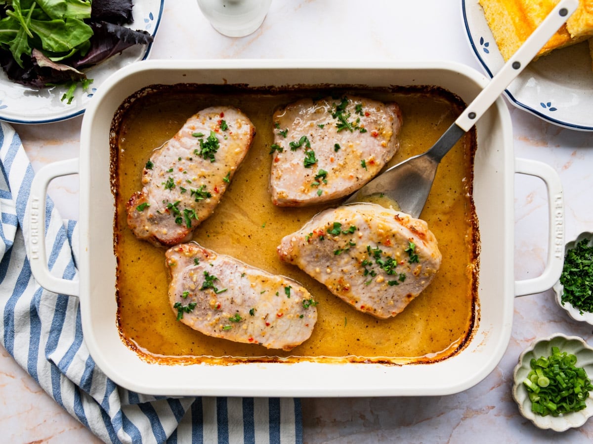 Horizontal overhead shot of baked pork chops in a white dish.