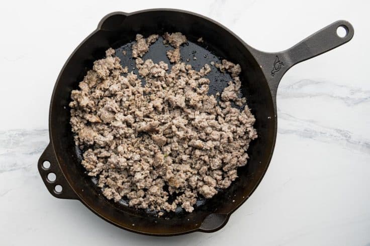 Overhead shot of browned breakfast sausage in a cast iron skillet.