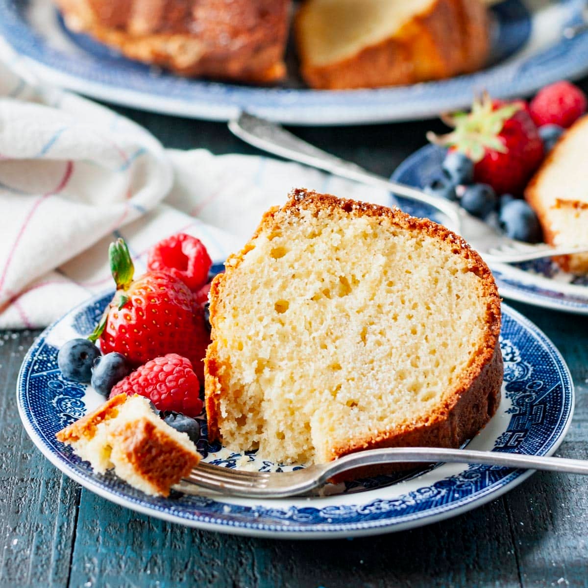 Fork taking a bite of sour cream pound cake on a plate.