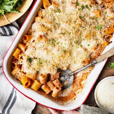 Square overhead shot of a pan of the best simple baked rigatoni recipe on a wooden table.