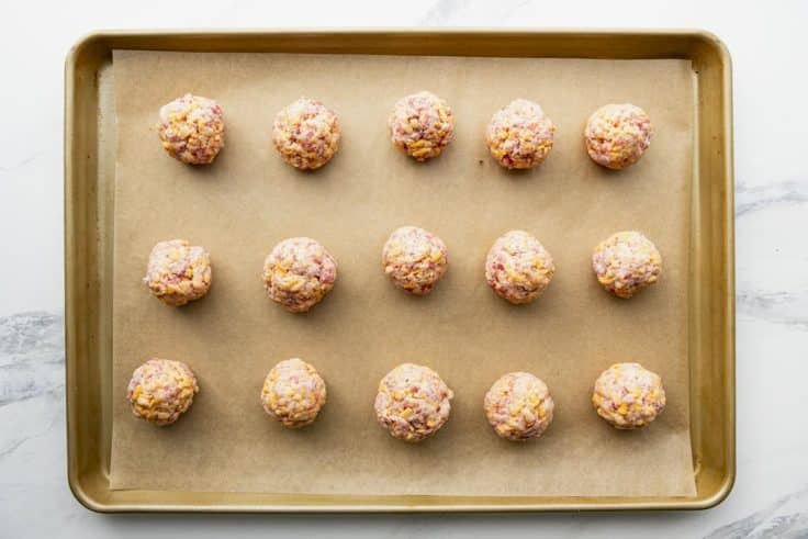 Bisquick sausage balls on a parchment lined sheet pan before baking.