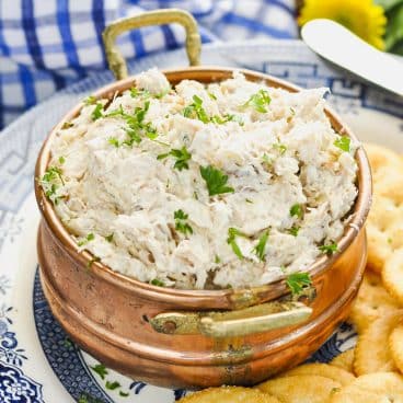 Close up square shot of a copper bowl full of crab dip.