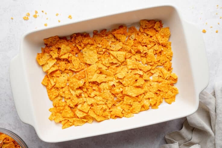 Crushed Doritos in the bottom of the white baking dish.