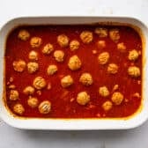 Meatballs and pasta added to the sauce in the baking dish.