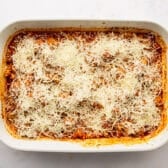 Adding cheese to the top of a meatball casserole recipe.